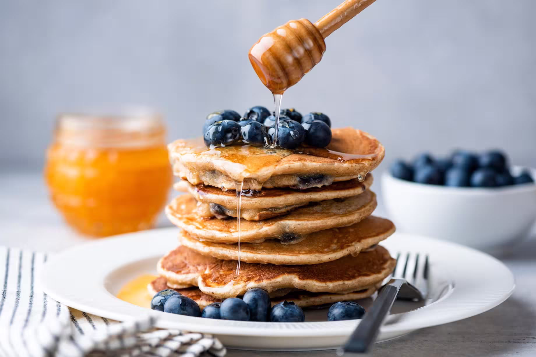 A stack of homemade oat pancakes topped with blueberries and syrup