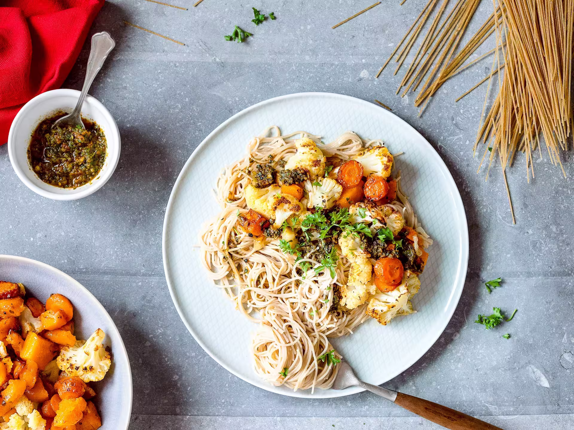 Plate of penne pasta with pesto and sun-dried tomato sauce, cauliflower, and carrots