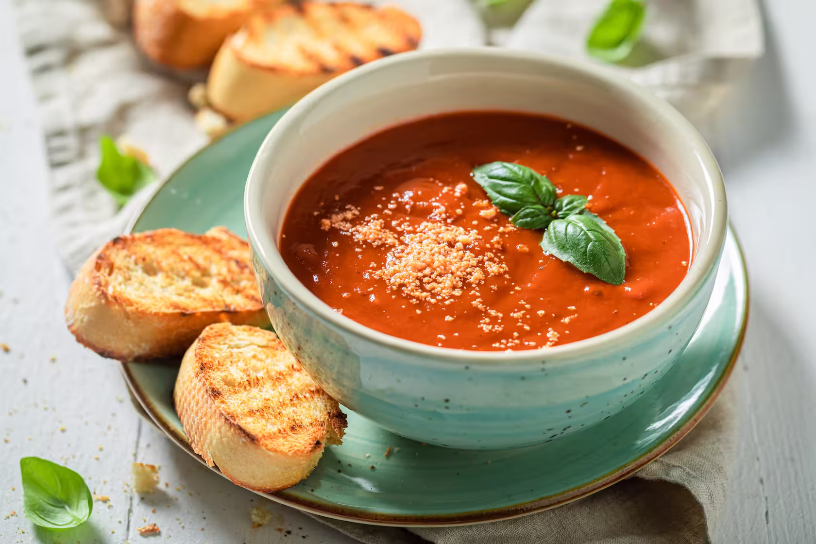A bowl of creamy tomato soup with a swirl of cream and basil